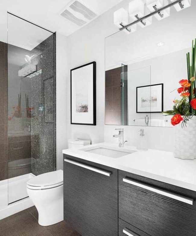 Les petites salles de bains sont agrandies de grands miroirs et de murs blancs et d'écrans de douche transparents