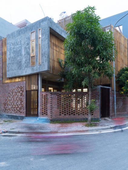 Façade de maison moderne avec des textures rustiques, de la brique, du béton et des tiges de bois