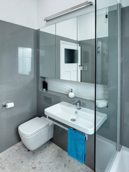 Petite salle de bain avec carrelage gris et toilettes blanches
