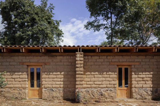 Façade de maison rustique avec murs en adobe, poutres apparentes en bois et toit