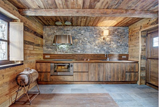 Conception de cuisine rustique, éléments bas en bois et murs en pierre, hotte en acier 
